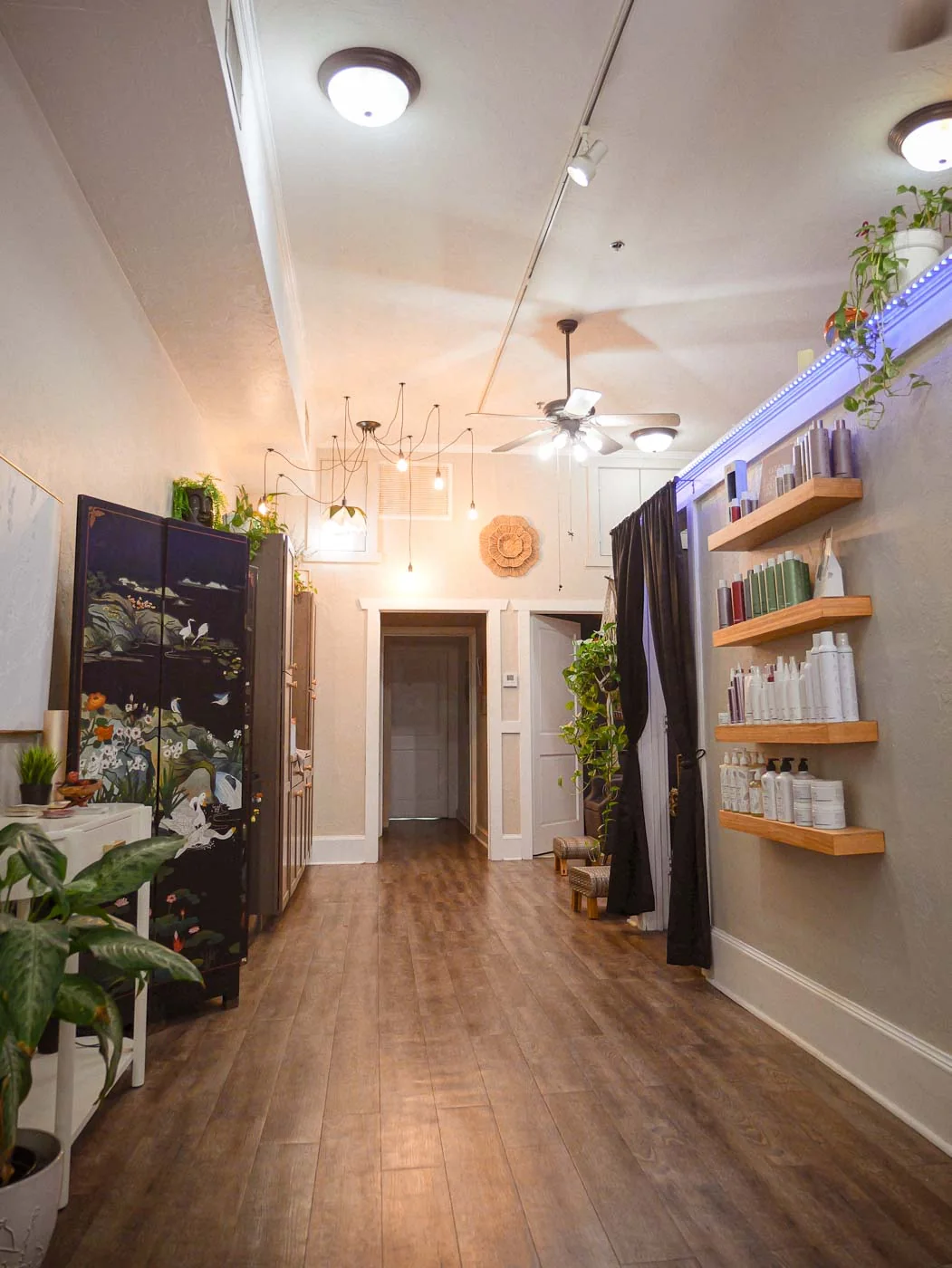A long hallway with wood floors and shelves leading through the salon