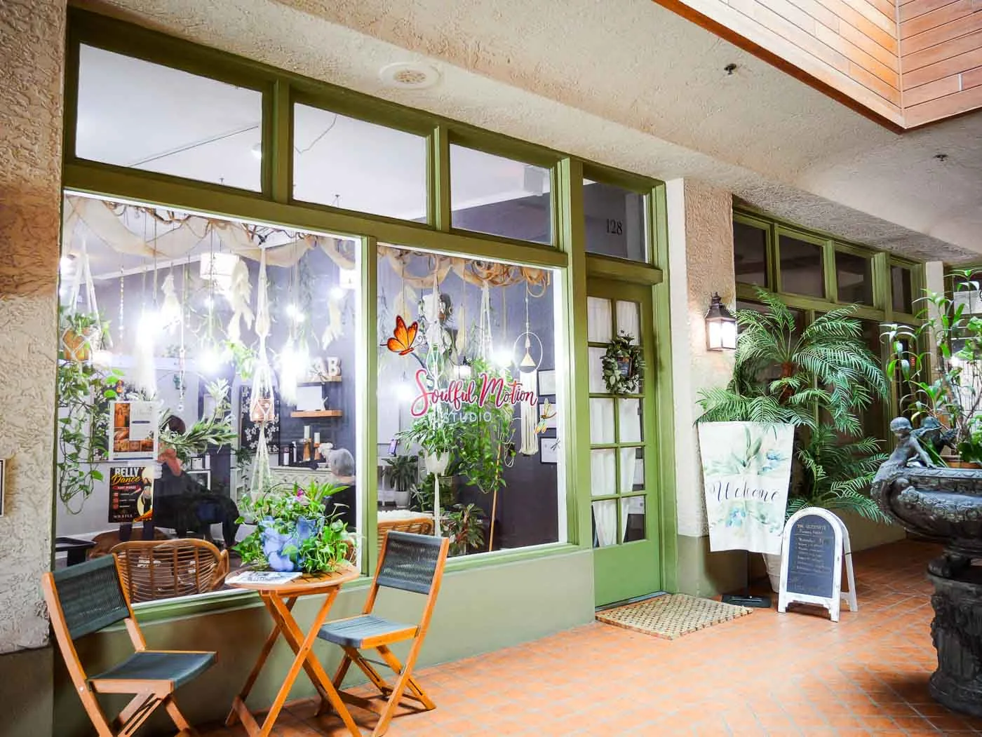 The salon’s green-framed front windows, café chairs and welcome sign in Kraaz Square