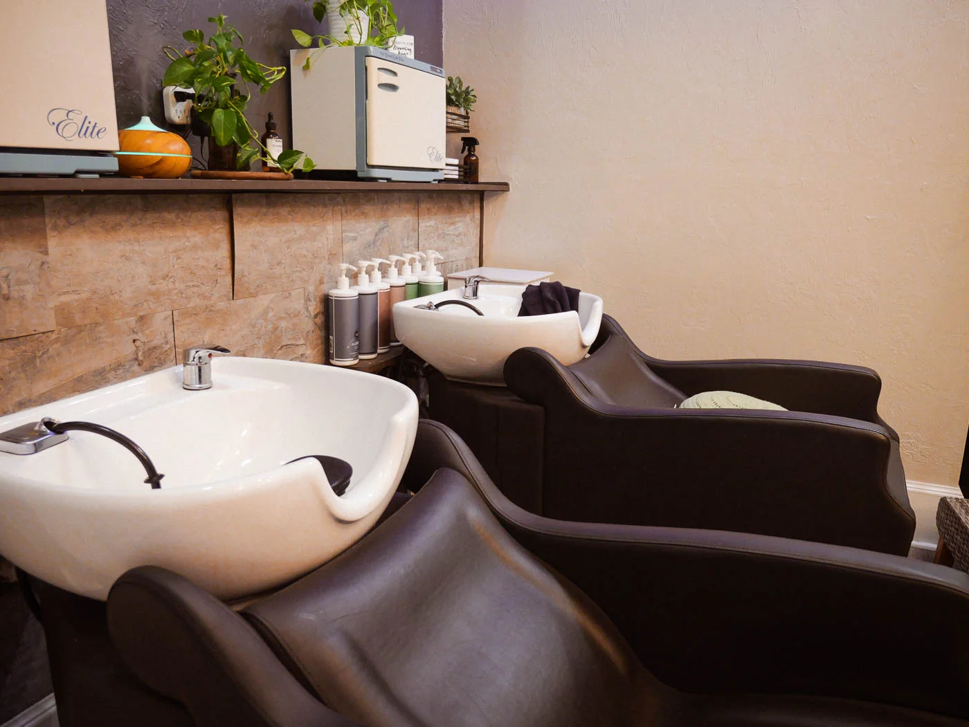 Two wash stations with white basins and leather chairs